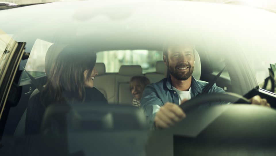 Looking inside a Hyundai through the windshield, a family in the car is looking happy.